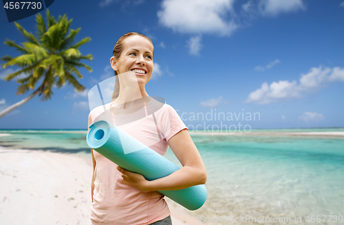 Image of happy smiling woman with exercise mat over beach