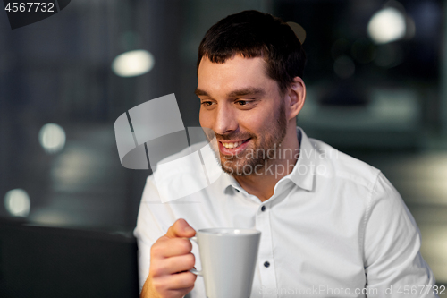 Image of businessman drinking coffee at night office