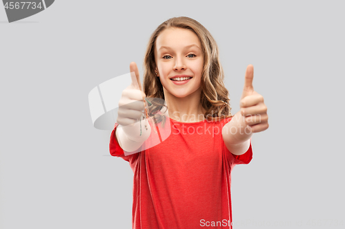 Image of smiling teenage girl in red showing thumbs up