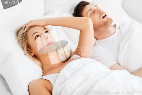 Image of unhappy woman in bed with snoring sleeping man