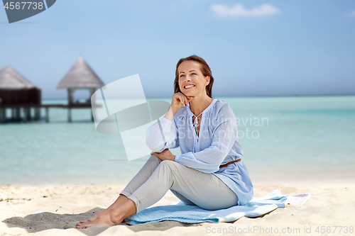 Image of happy woman sitting on summer beach