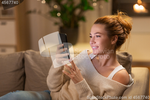 Image of happy young woman with smartphone at home