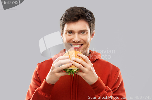 Image of happy young man eating hamburger