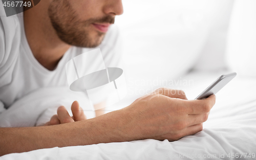 Image of close up of man with smartphone in bed in morning