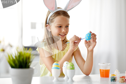 Image of happy girl coloring easter eggs at home