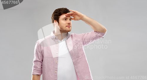 Image of happy young man looking far over grey background