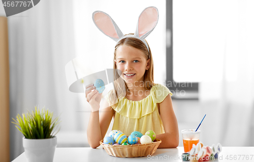 Image of happy girl with colored easter eggs at home