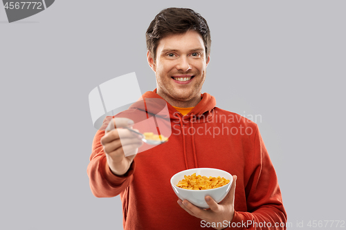 Image of smiling young man in red hoodie eating cereals