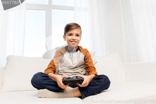 Image of happy boy with gamepad playing video game at home