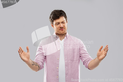 Image of displeased young man showing size of something
