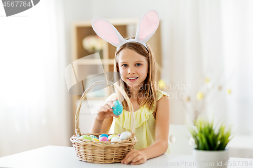 Image of happy girl with colored easter eggs at home