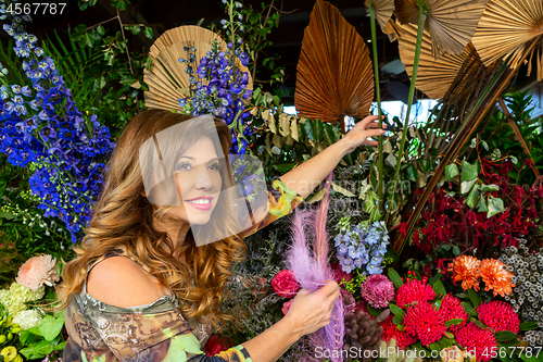 Image of Woman standing outside a florist choosing flowers