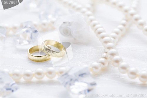 Image of Two golden rings with pearl necklace and on white background