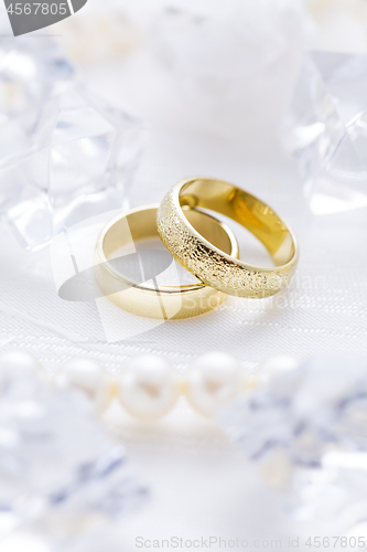 Image of Two golden rings with pearl necklace and on white background