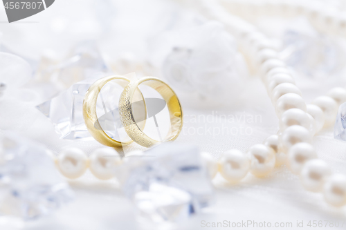 Image of Two golden rings with pearl necklace and on white background