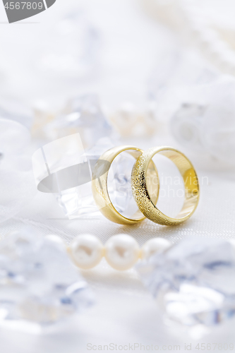 Image of Two golden rings with pearl necklace and on white background