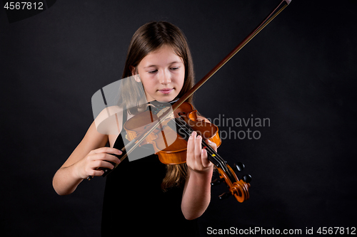 Image of Young professional violinist playing and exercising on black background