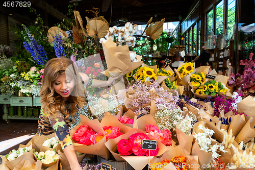 Image of Woman on footpath choosing bunches of flowers from florist