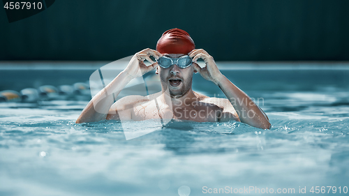 Image of fit swimmer in cap at pool