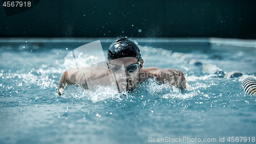 Image of dynamic and fit swimmer in cap breathing performing the butterfly stroke