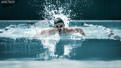 Image of dynamic and fit swimmer in cap breathing performing the butterfly stroke