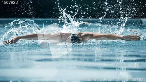 Image of dynamic and fit swimmer in cap breathing performing the butterfly stroke