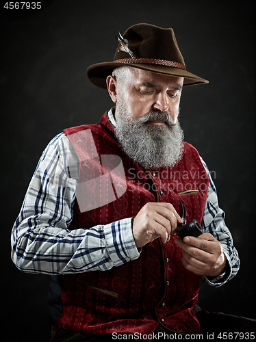 Image of dramatic portrait of senior smoking tobacco pipe