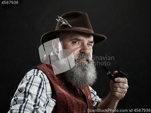 Image of dramatic portrait of senior smoking tobacco pipe