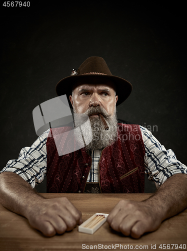 Image of bearded man clogs the tobacco in pipe