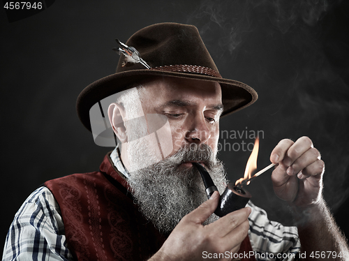 Image of dramatic portrait of senior smoking tobacco pipe