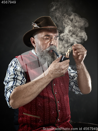 Image of dramatic portrait of senior smoking tobacco pipe