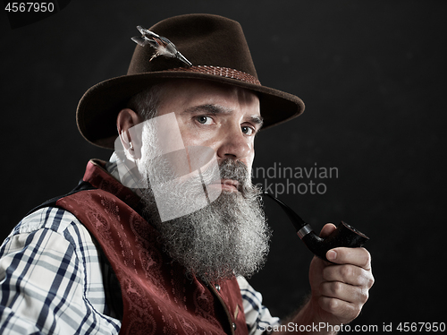 Image of dramatic portrait of senior smoking tobacco pipe