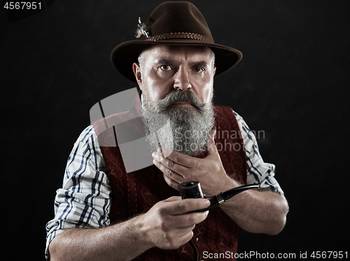 Image of dramatic portrait of senior smoking tobacco pipe