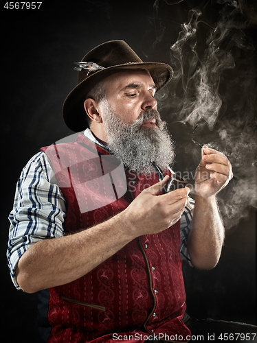 Image of dramatic portrait of senior smoking tobacco pipe
