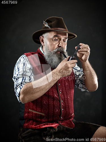 Image of Black and white dramatic portrait of senior smoking tobacco pipe