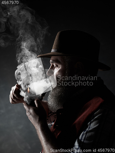 Image of Black and white dramatic portrait of senior smoking tobacco pipe