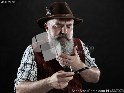 Image of dramatic portrait of senior smoking tobacco pipe