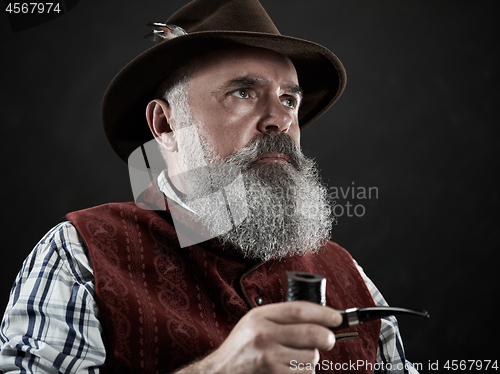 Image of dramatic portrait of senior smoking tobacco pipe