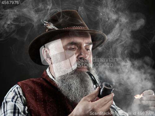 Image of dramatic portrait of senior smoking tobacco pipe