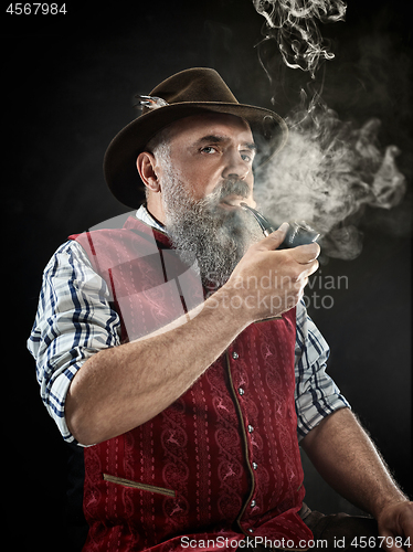 Image of dramatic portrait of senior smoking tobacco pipe