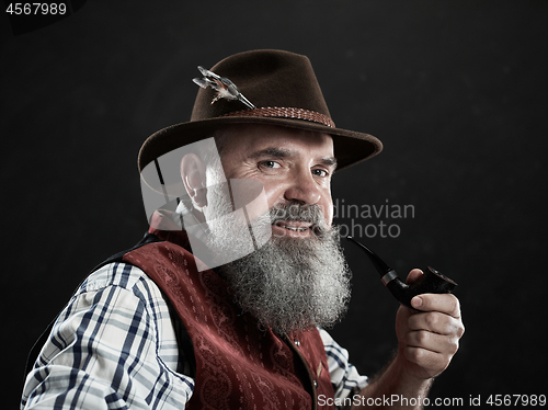 Image of dramatic portrait of senior smoking tobacco pipe