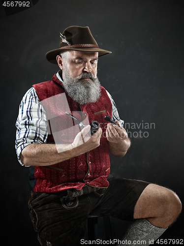 Image of dramatic portrait of senior smoking tobacco pipe