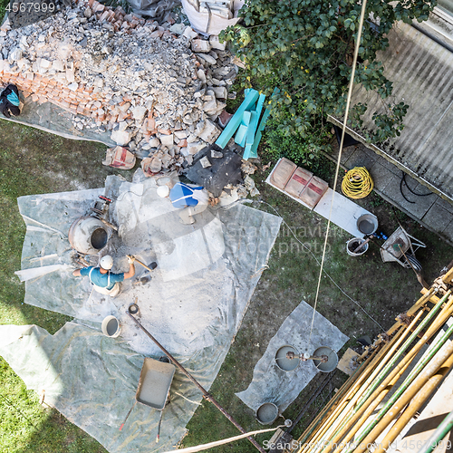 Image of Top view of authentic builder men working with shovel during concrete cement solution mortar preparation in mixer at construction site