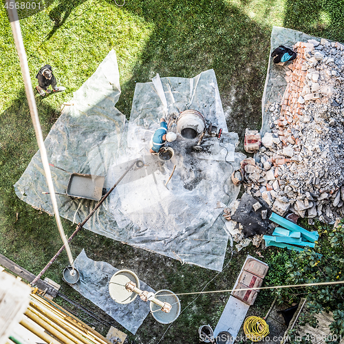 Image of Top view of authentic builder men working with shovel during concrete cement solution mortar preparation in mixer at construction site