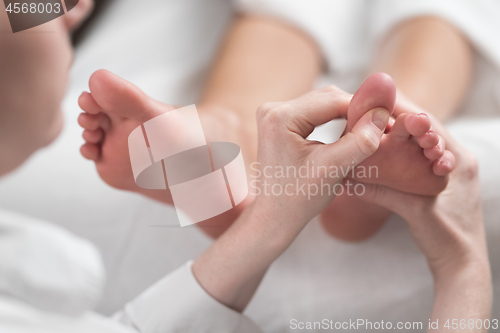 Image of Professional female masseur giving reflexology massage to woman foot