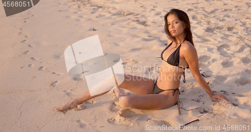 Image of Asian female relaxing on sand during sunset