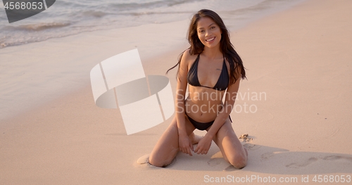 Image of Positive woman resting on seashore on sunset