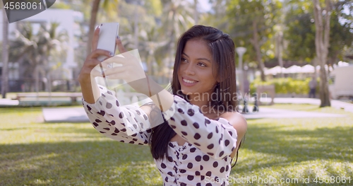 Image of Smiling Asian woman taking selfie on smartphone with smile