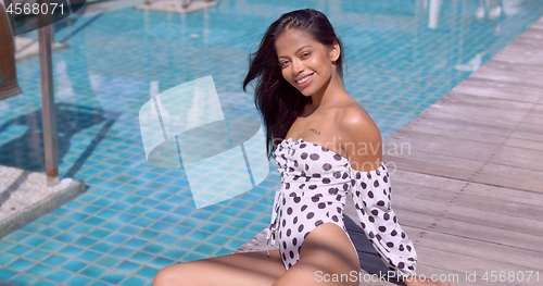 Image of Adult ethnic woman in swimwear resting at poolside