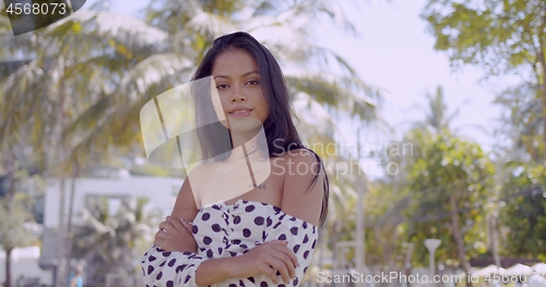 Image of Confident Asian woman in dress with open shoulder looking at camera folding hands